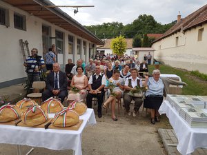 A közönség, a nemzeti szalaggal átkötött új kenyér és jobb oldalon Király Kata könyve a kesztölci népdalokról